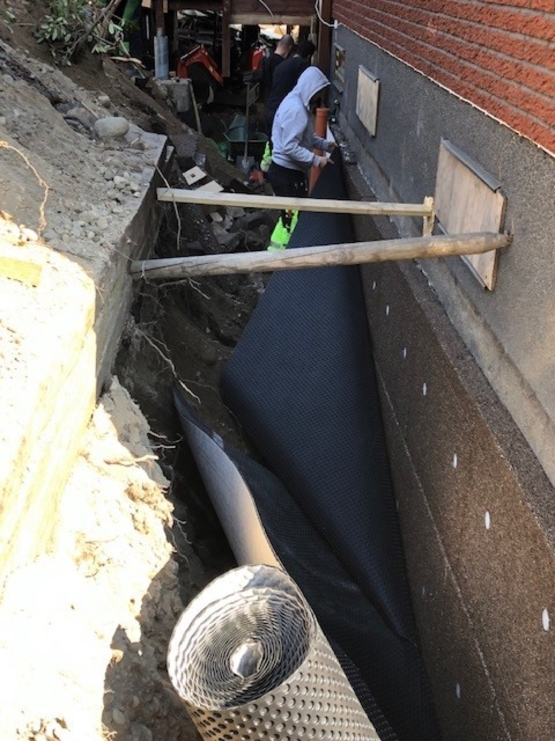 Platon fuktskyddsmatta rullas ut i dräneringsschakt längs husgrund